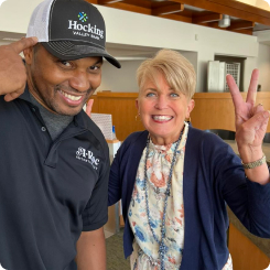 Tammy Bobo smiling and giving a peace sign with Aaron Thomas smiling and pointing at his HVB hat.