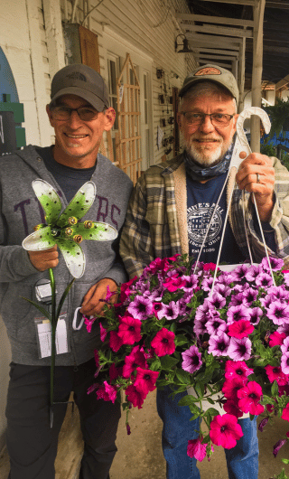 Owners at White's Mill holding flowers and a lawn ornament.
