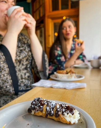 Close up of a pastry at Fluff Bakery with women talking in the background
