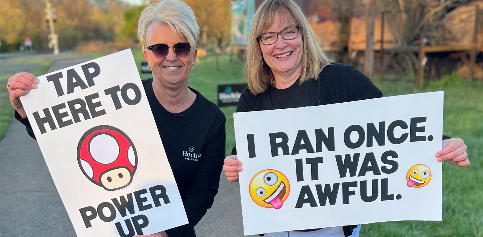 Two bankers holding up signs encouraging runners participating in the Athens Marathon.