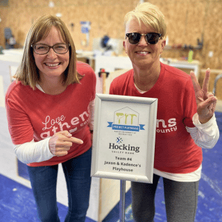 Bankers standing by Team sponsor signage for Habitat for Humanity Project Playhouse.