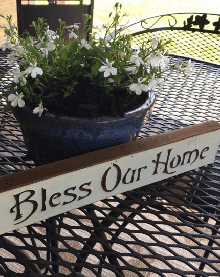 Patio table with flowers and bless our home sign