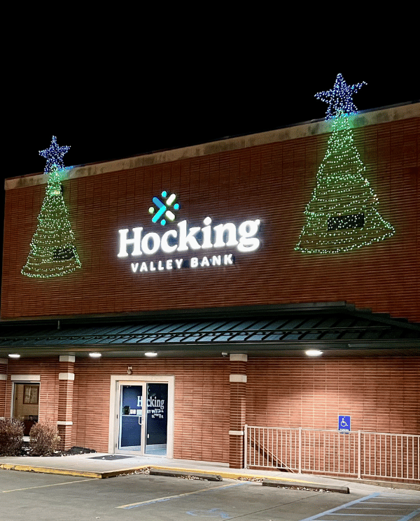 Exterior of bank with two large Christmas trees on either side of the bank logo
