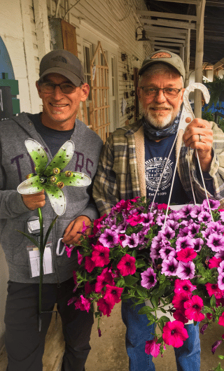 Owners at White's Mill holding flowers and a lawn ornament. 