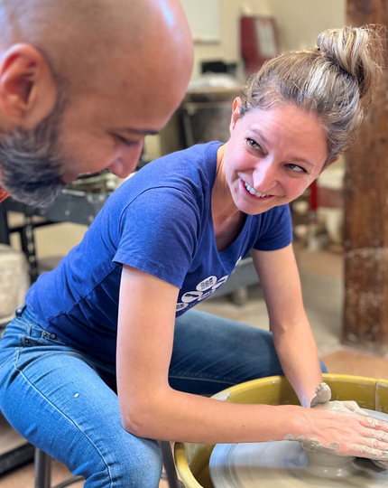 Two people smiling and working with a potters wheel at Dairy Barn Arts Center