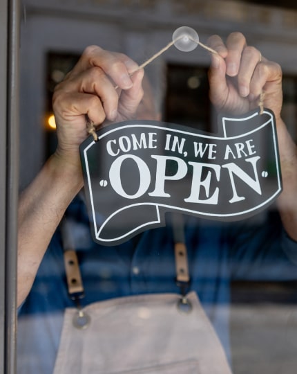 Business owner hanging up an open for business sign