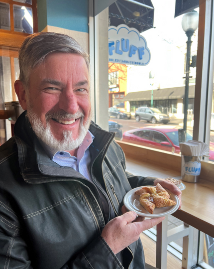 Mayor Steve Patterson holding a pastry at Fluff Bakery