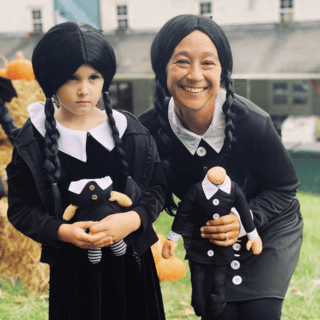 Banker and child dressed up like Wednesday from The Addams Family.